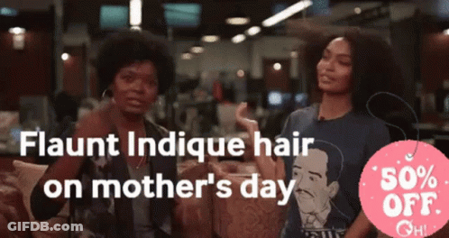 Two Women Are Sitting In Front Of A Sign That Says Flaunt Indicue Hair On Mother 'S Day GIF