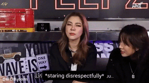 Two Women Are Sitting In Front Of A Sign That Says " Wave Is " GIF