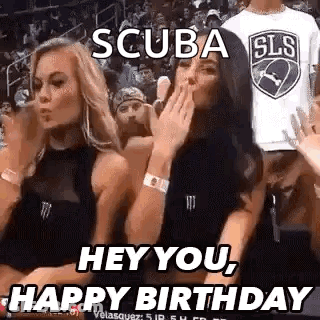 Two Women Are Sitting In The Stands At A Basketball Game And One Is Blowing A Kiss . GIF