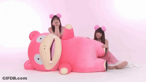 Two Women Are Sitting Next To A Pink Stuffed Animal . GIF