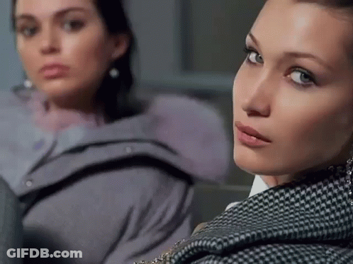 Two Women Are Sitting Next To Each Other And One Is Wearing A Plaid Jacket GIF
