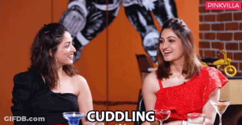 Two Women Are Sitting Next To Each Other And The Word Cuddling Is On The Bottom GIF