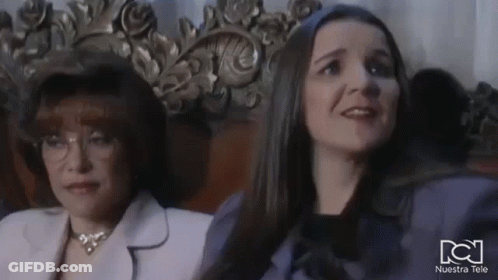 Two Women Are Sitting Next To Each Other In A Chair In A Room . GIF