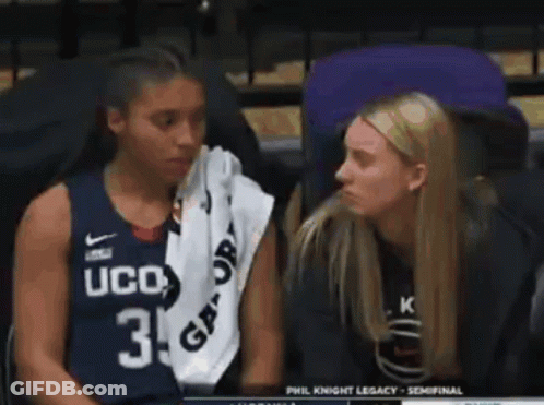 Two Women Are Sitting Next To Each Other In A Stadium . One Of The Women Is Wearing A Ucd Jersey . GIF