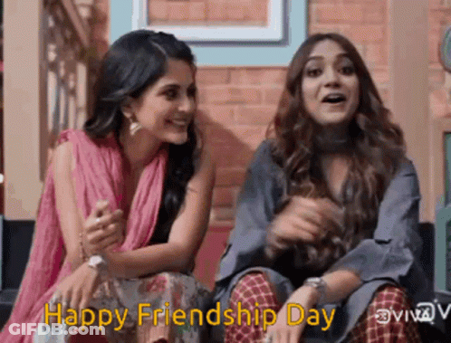 Two Women Are Sitting Next To Each Other In Front Of A Brick Wall And Smiling . GIF
