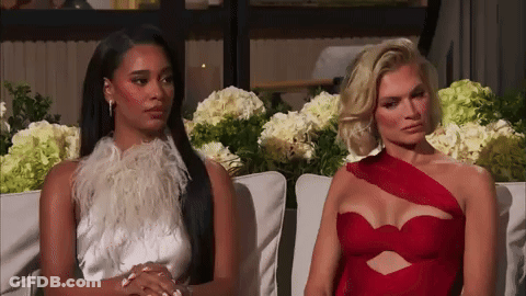 Two Women Are Sitting Next To Each Other On A Couch And One Is Wearing A Red Dress GIF