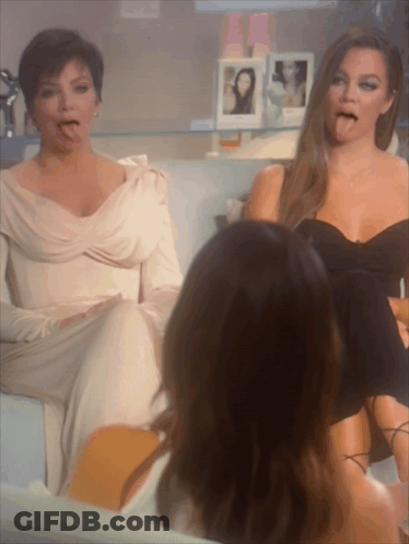 Two Women Are Sitting On A Couch And One Is Sticking Her Tongue Out GIF