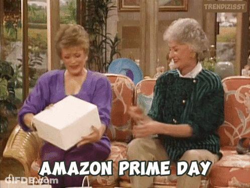Two Women Are Sitting On A Couch And One Of Them Is Holding An Amazon Prime Day Gift GIF