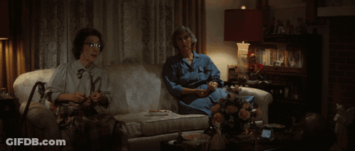 Two Women Are Sitting On A Couch One Is Knitting The Other Is Drinking Tea GIF