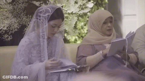 Two Women Are Sitting On A Couch Reading Books . GIF