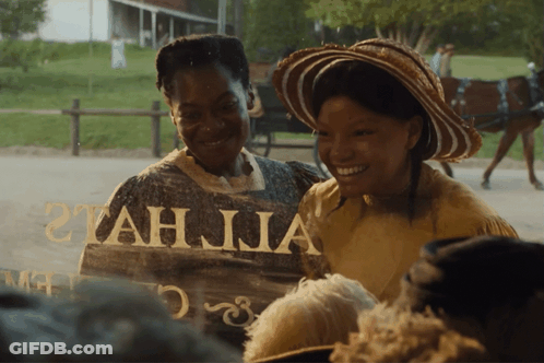 Two Women Are Smiling In Front Of A Sign That Says Tah Jia GIF