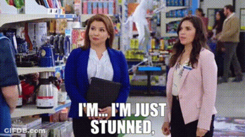 Two Women Are Standing In A Store Talking To Each Other And One Of Them Is Holding A Clipboard . GIF