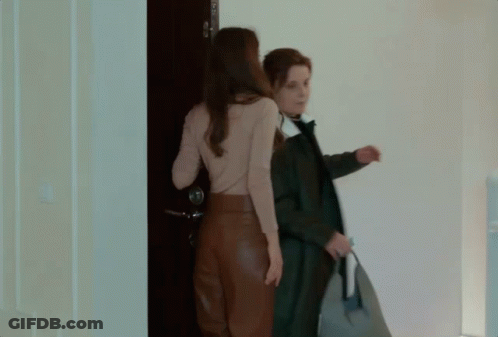 Two Women Are Standing In Front Of A Blue Door GIF