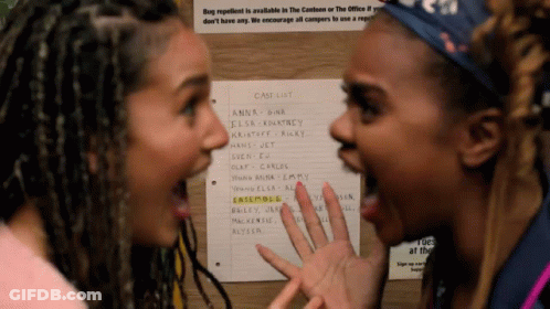 Two Women Are Standing In Front Of A Case List On A Wall GIF