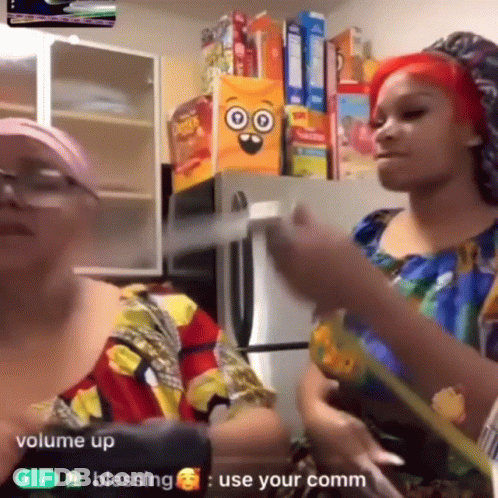 Two Women Are Standing In Front Of A Refrigerator With Boxes Of Cereal On The Shelf Behind Them . GIF