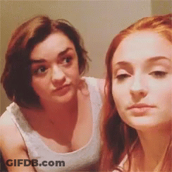 Two Women Are Standing Next To Each Other And Looking At Each Other . One Of The Women Is Wearing A White Tank Top . GIF