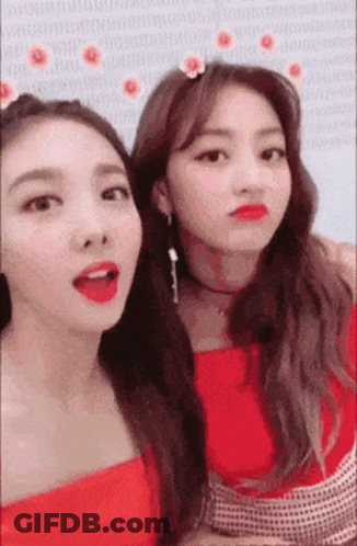 Two Women Are Standing Next To Each Other And Making Funny Faces . One Of The Women Is Wearing A Flower In Her Hair . GIF