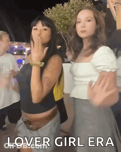 Two Women Are Standing Next To Each Other And One Of Them Is Blowing A Kiss While The Other Says Lover Girl Era GIF