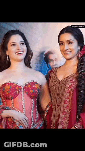 Two Women Are Standing Next To Each Other And Smiling . One Of The Women Is Wearing A Corset . GIF