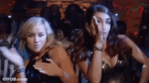 Two Women Are Standing Next To Each Other In A Club And Dancing . GIF