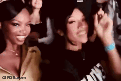 Two Women Are Standing Next To Each Other In A Crowd At A Party And Smiling . GIF