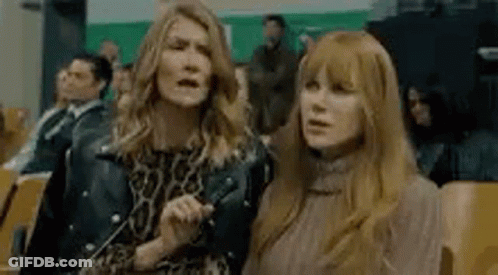 Two Women Are Standing Next To Each Other In A Crowd Of People In A Theater . GIF