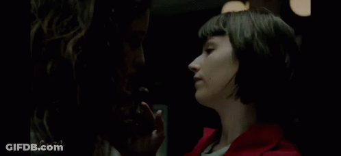 Two Women Are Standing Next To Each Other In A Dark Room . GIF