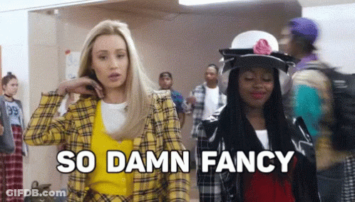 Two Women Are Standing Next To Each Other In A Hallway And One Of Them Is Wearing A Yellow Plaid Jacket . GIF