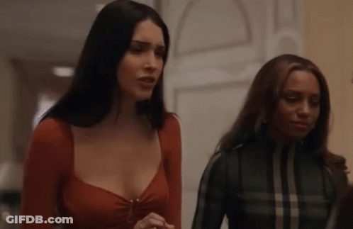 Two Women Are Standing Next To Each Other In A Hallway And Talking . GIF