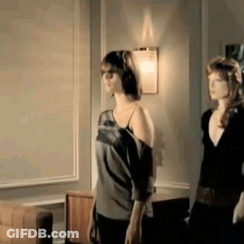 Two Women Are Standing Next To Each Other In A Living Room In Front Of A Wall . GIF