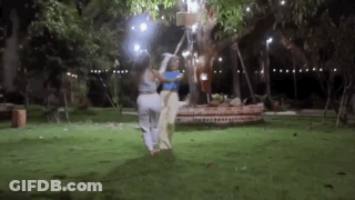 Two Women Are Standing Next To Each Other In A Park At Night . GIF