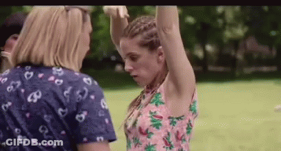 Two Women Are Standing Next To Each Other In A Park With Their Arms Up . GIF