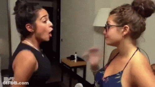 Two Women Are Standing Next To Each Other In A Room And Having A Fight . GIF
