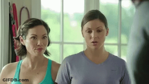 Two Women Are Standing Next To Each Other In A Room And Looking At Each Other . GIF