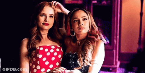 Two Women Are Standing Next To Each Other In A Room . One Of The Women Is Wearing A Red Polka Dot Dress . GIF