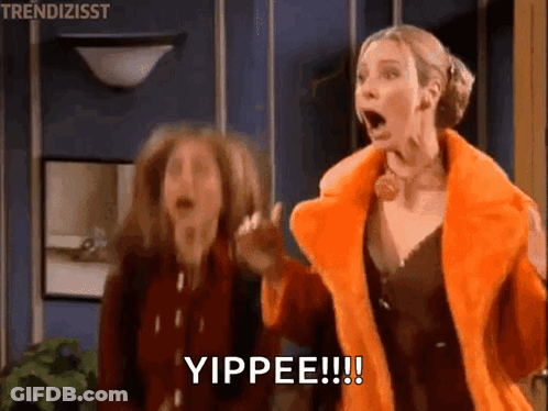 Two Women Are Standing Next To Each Other In A Room With Their Mouths Open And One Of Them Is Wearing An Orange Fur Coat GIF