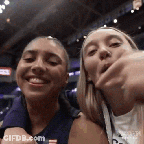 Two Women Are Standing Next To Each Other In A Stadium And Smiling At The Camera . GIF
