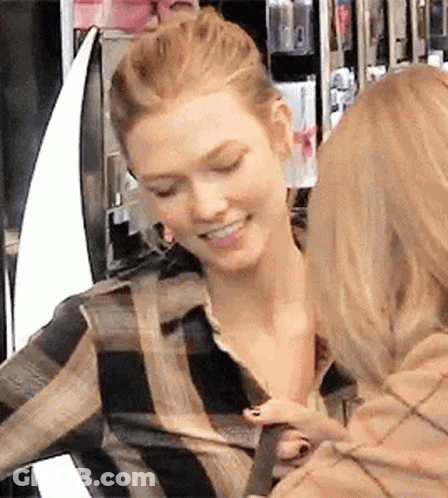 Two Women Are Standing Next To Each Other In A Store And One Of Them Is Holding The Other 'S Arm . GIF