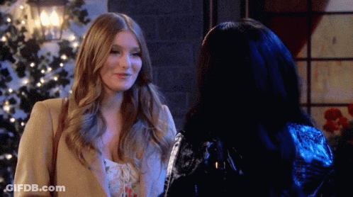 Two Women Are Standing Next To Each Other In Front Of A Christmas Tree And Smiling GIF