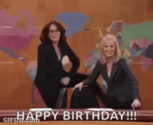 Two Women Are Standing Next To Each Other In Front Of A Desk . GIF