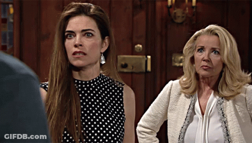 Two Women Are Standing Next To Each Other In Front Of A Door GIF
