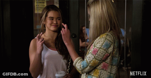 Two Women Standing Next To Netflix Sign GIF