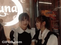 Two Women Are Standing Next To Each Other In Front Of A Sign That Says Una GIF