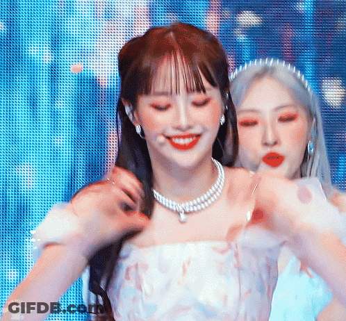 Two Women Are Standing Next To Each Other On A Stage . One Of The Women Is Wearing A Pearl Necklace . GIF