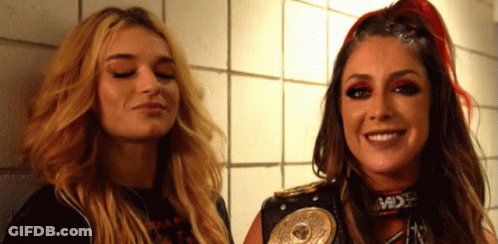 Two Women Are Standing Next To Each Other With One Wearing A Belt That Says ' Mdx ' On It GIF