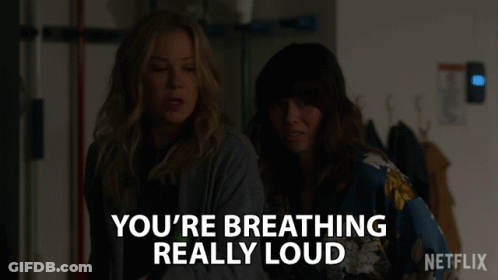 Two Women Are Standing Next To Each Other With The Words " You 'Re Breathing Really Loud " GIF