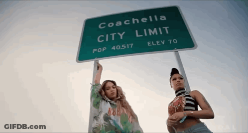 Two Women Are Standing Under A Sign That Says Coachella City Limit GIF