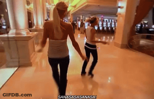 Two Women Are Walking Down A Hallway In A Casino And One Of Them Is Dancing . GIF