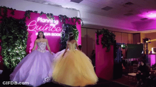Two Women Are Walking Down A Runway In Front Of A Sign That Says Planning Quince GIF