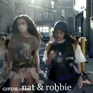 Two Women Are Walking Down A Street And The Words Nat And Robbie Are Visible GIF